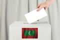 Maldives Vote concept. Voter hand holding ballot paper for election vote on polling station