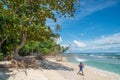 Maldivian boy with surfing board going for surfing into ocean at the beach at the tropical island