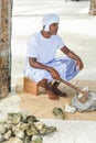 Maldivian construction worker in national maldivian clothes sitting with axe near pile of rocks