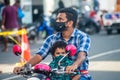 Maldivian man with child wearing masks while driving bike on the street during covid-19