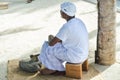 Maldivian muslim construction worker in traditional national maldivian clothes sitting near the coral rocks