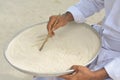 Maldivian teacher writing in dhivehi on the sand using wooden stick