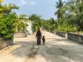 A Maldivian woman with her child walks down the street