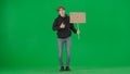 A male activist holds a blank poster and shows a thumbs up. A young man in casual clothes holds a placard on a green Royalty Free Stock Photo