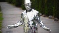 Male actor wearing unusual mirror costume frozes like a statue on nature back at city street. Restaurant Dva Bobra. June