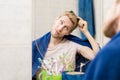 Male adult comb hair in bathroom looking in the mirror with a towel