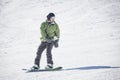 Male adult snowboarder riding down a groomed snow hill