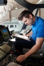 Male Aero Engineer With Clipboard Working In Helicopter Cockpit