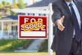 Male Agent Reaching for Hand Shake in Front of Sold For Sale Sign