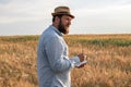 Male agronomist stands in the field and records, analyzes the growth of plants