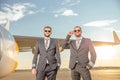 Male airline captains standing near airplane at airport