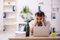 Young alcohol addicted employee sitting in the office