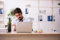 Young alcohol addicted employee sitting in the office