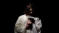 Male alike Jesus Christ standing in darkness holding holy bible, confession Royalty Free Stock Photo