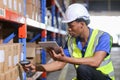 Male american african factory company employee scanning box checking number of products on goods shelves with tablet in warehouse