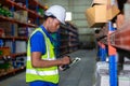 Male american african factory company employee scanning box checking number of products on goods shelves with tablet in warehouse