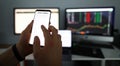 Male analyst hands using smartphone to follow stock index growth