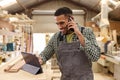Male Apprentice With Digital Tablet Working As Carpenter In Furniture Workshop Making Phone Call Royalty Free Stock Photo