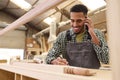 Male Apprentice Working As Carpenter In Furniture Workshop Making Phone Call Royalty Free Stock Photo