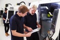 Male Apprentice Working With Engineer On CNC Machinery