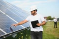 Male arab engineer standing on field with rows of solar panels Royalty Free Stock Photo
