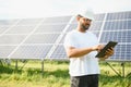 Male arab engineer standing on field with rows of solar panels Royalty Free Stock Photo
