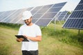 Male arab engineer standing on field with rows of solar panels Royalty Free Stock Photo