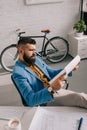 Male architect in blue jacket sitting and looking at paper