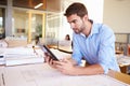 Male Architect With Digital Tablet Studying Plans In Office