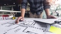 A male architect measuring and marking the scale ratio of sizes of a complicated blueprint