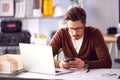 Male Architect In Office With Laptop Working On Plan At Desk Text Messaging On Mobile Phone Royalty Free Stock Photo