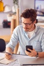 Male Architect In Office Working At Desk Making Online Purchase Using Credit Card On Mobile Phone Royalty Free Stock Photo