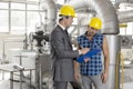 Male architect with worker discussing over clipboard in industry Royalty Free Stock Photo