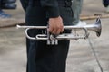 A male army soldier holds a silver trumpet at an outdoor show.