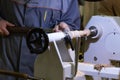 A male artisan works on a wood lathe, curly carving, hobby. The process of manufacturing wooden handicrafts, work space in the