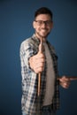 Male artist holding paintbrush on color background