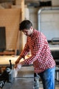 Male artist works with a wooden board at the planer, joiner's sh