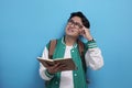 Male Asian student studying hard, reading a book against blue background Royalty Free Stock Photo