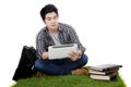 Male Asian student uses tablet on grass