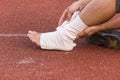 Male athlete applying compression bandage onto ankle injury of a football player,