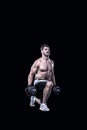 Male athlete doing knee-bends with dumbbells isolated on black