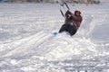 A male athlete engaged in snow kiting on the ice of a large snowy lake. He goes skiing in the snow.