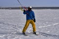 A male athlete engaged in snow kiting on the ice of a large snowy lake. He goes skiing in the snow. Winter sunny frosty day