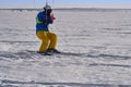 A male athlete engaged in snow kiting on the ice of a large snowy lake. He goes skiing in the snow.