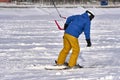 A male athlete engaged in snow kiting on the ice of a large snowy lake. He goes skiing in the snow. Winter sunny frosty day