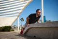 Lifestyle portrait of a male athlete doing exercises on arms and back muscles, pushing up during bodyweight training