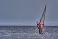 A male athlete is interested in windsurfing. He moves on a Sailboard on a large lake