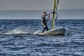 A male athlete is interested in windsurfing. He moves on a Sailboard on a large lake