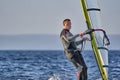 A male athlete is interested in windsurfing. He moves on a Sailboard on a large lake