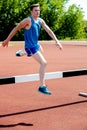 Male athlete jumping hurdle